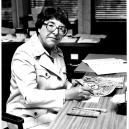 Professor Betty Roots sits at a desk in 1974 examining electron micrographs of nerve cells