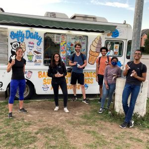 Prof Christina Guzzo and five lab members by an ice cream truck, smiling as they enjoy their ice cream