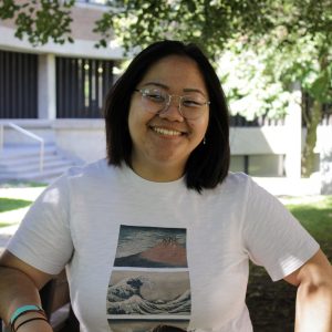 Jade Zhang smiles at the camera, standing in the shade of New College courtyard